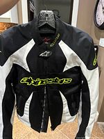 Front view of black and white Alpinestars motorcycle jacket with yellow branding.
