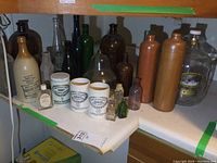 Wide shot of collection showing diverse bottles including stoneware and glass bottles with labels and embossed text.
