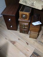 Photo showing collection of vintage wooden sewing machine boxes and small wooden boxes on wooden floor, highlighting size and designs.