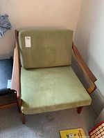 Front view of teak lounge chair with green cushion
