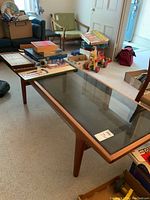 Front view of the teak coffee table with items placed on top, showing overall structure and table top finish