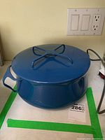 Full view of blue Dansk pot with lid showing exterior and top crossbar handle