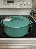 Green Dansk enamel pot with matching lid placed on stove, showing whole pot and lid handle design.