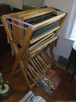 Assembled loom with straps and a bag of parts at base