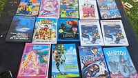 Photo showing 14 kids DVDs arranged on a surface, the titles visible include Barbie Fairytopia, Jack and the Beanstalk, Space Chimps, Horton Hears a Who, The Pirates, Brave, Rio, Barbie Mariposa, Legion of Super Heroes, Jacques Cousteau's Voyage to the Edge of the World, and two interactive DVDs.