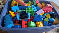 Blue bin filled with colorful large plastic Megablocks and foam blocks of various shapes and colors.