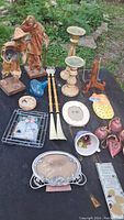 Full view of lot showing various decor items including paper mache figures, candle sticks, wire picture frame, porcelain plates, glass bird figurine, utensils, key holder and small card
