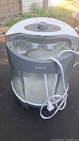 White Sunbeam humidifier with clear water tank and attached power cord, shown outdoors