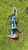 Full view of the foldable ice fishing auger showing blue shaft, red base plate, and silver crank handle with black grip.