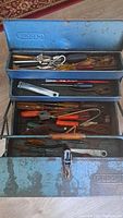 Photo of open blue Gedore metal tool chest showing various vintage hand tools inside including pliers, screwdrivers, and other tools.