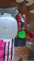 Full overview of lot items showing casserole dish, Scotch fasteners, green pill containers, red mug, glass cups, and belt holder.