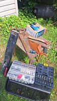 Overview of the lot showing several hand tools on wooden boards, a black case with sockets, a clear plastic case with rotary tool bits, a small screwdriver, and a small hatchet.