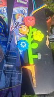 Photo showing three flower-shaped bike chalk attachments and a multicolor flower-shaped garden sprinkler.
