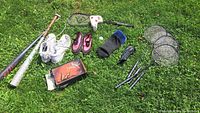 Lot contents on grass: baseball bats, New Balance cleats, watershoes, body shaper, club cozies, badminton and squash rackets