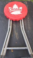 Top view of the stool showing the red plastic top shaped like a bottle cap with Canada maple leaf logo.