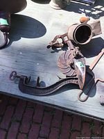 Photo of a cast iron antique cherry pitter with clamp and lever on a wooden surface, showing patina and wear.