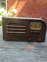 Front view of antique Spartan tube radio with wooden cabinet, tuning dial labeled 'Sparton', speaker grill, and control knobs.