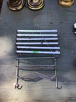 Metal soap holder and rack accessory with multiple slats and hooks below.