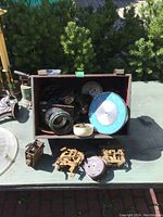 Top down view of wooden box containing various steam clock components including clock dials, movements, and other parts.