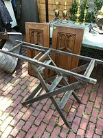 Wooden vintage wallpaper hanger ladder/table with rectangular frame and folding legs laid on brick patio, showing side angle.