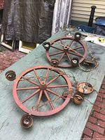 Pair of vintage wagon wheel chandeliers with metal candle cups, viewed from above on outdoor table.