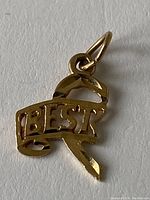 Close-up of the pendant showing the front side with the word 'BEST' in gold on a ribbon design and the bail.