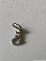 Clear image of the front side of the 14K white gold 'J' pendant on a white background.