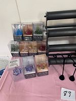 Full view of ten boxed colorful art glass ring valet display items arranged in two piles, with the black metal bracelet display stand to the right.