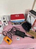 Overview photo of the lot showing all items on a pink surface including the EVO VR headset box, microphone box, charger with cable, and other small accessories.