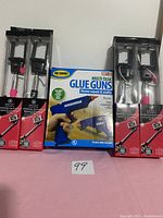 Photo showing two boxed extendable selfie wand tripods and one boxed set of multi-task glue guns for home repair and crafts.