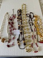 Top view of all seven necklaces laid out to show variety and length.