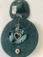Sterling silver heart-shaped pendant necklace displayed on green velvet fabric inside matching jewelry box.