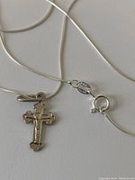 Close-up of the sterling silver cross pendant, chain, and clasp with the 925 purity tag.