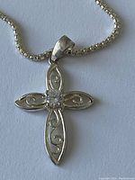 Front view of the sterling silver cross pendant with clear stone on a square-linked silver chain against a white background.