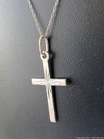 Close-up of sterling silver cross pendant showing starburst engraving and bail attachment