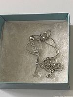 Sterling silver necklace with heart-shaped pendant inside blue jewelry box.