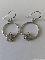 Front view of the pair of sterling silver earrings showing circular hoops with rose detail at the bottom.