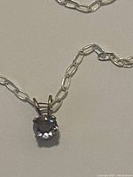 Image showing oval link sterling silver chain with attached round violet-blue tanzanite pendant in four-prong setting.
