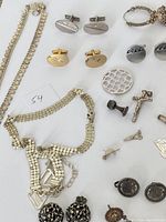 Overview of vintage silver and sterling silver jewelry including cufflinks, necklaces, pendants, and pins against a white background.