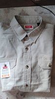 Wrangler short sleeve button-down shirt folded showing front with buttons and chest pockets.