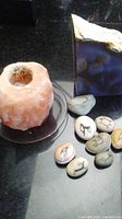 Himalayan salt candle holder and painted stones on black surface with box in background