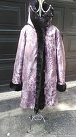 Full view of reversible coat on mannequin showing patterned side with black trim and cuffs.