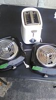 Overview of the two black Toastmaster hot plate elements and the white two-slice toaster placed on a table.