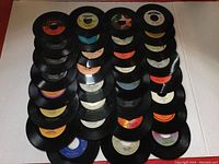 Array of 30 vinyl 45 RPM records laid out in a grid, showing various labels and colors.
