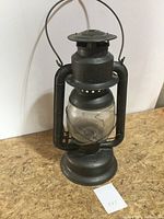 Front right view of black metal lantern with glass globe, showing overall condition and handle.