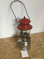 Side view showing red top with paint wear and stainless steel bottom with reflective surface and some marks.