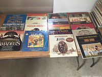 Overhead photo showing 16 LP records arranged on two tables in two stacks, featuring various movie soundtracks and original cast albums.