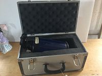 Meade telescope securely placed in a foam-lined aluminum carrying case with lid open showing the telescope body.