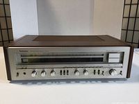 Front view of the Technics SA-616 stereo receiver showing the tuner dial, control knobs, power switch and headphone jack with wooden side panels.