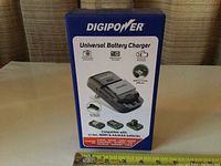 Photo of the front of the DIGIPOWER Universal Battery Charger box showing product image and compatible battery types.